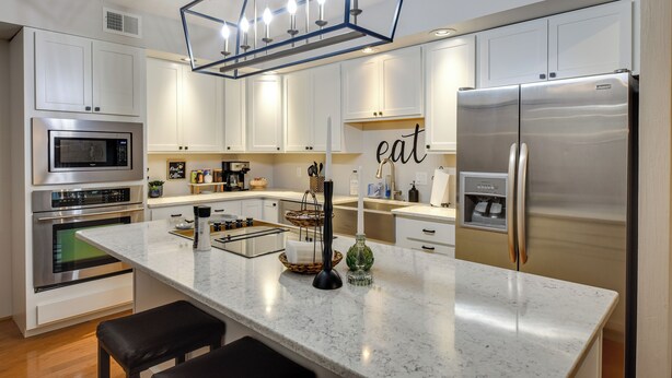 Een moderne keuken met witte kasten, roestvrijstalen apparatuur en een marmeren aanrecht.