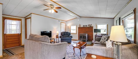 A spacious living room with a fireplace, two sofas, a coffee table, and a ceiling fan.