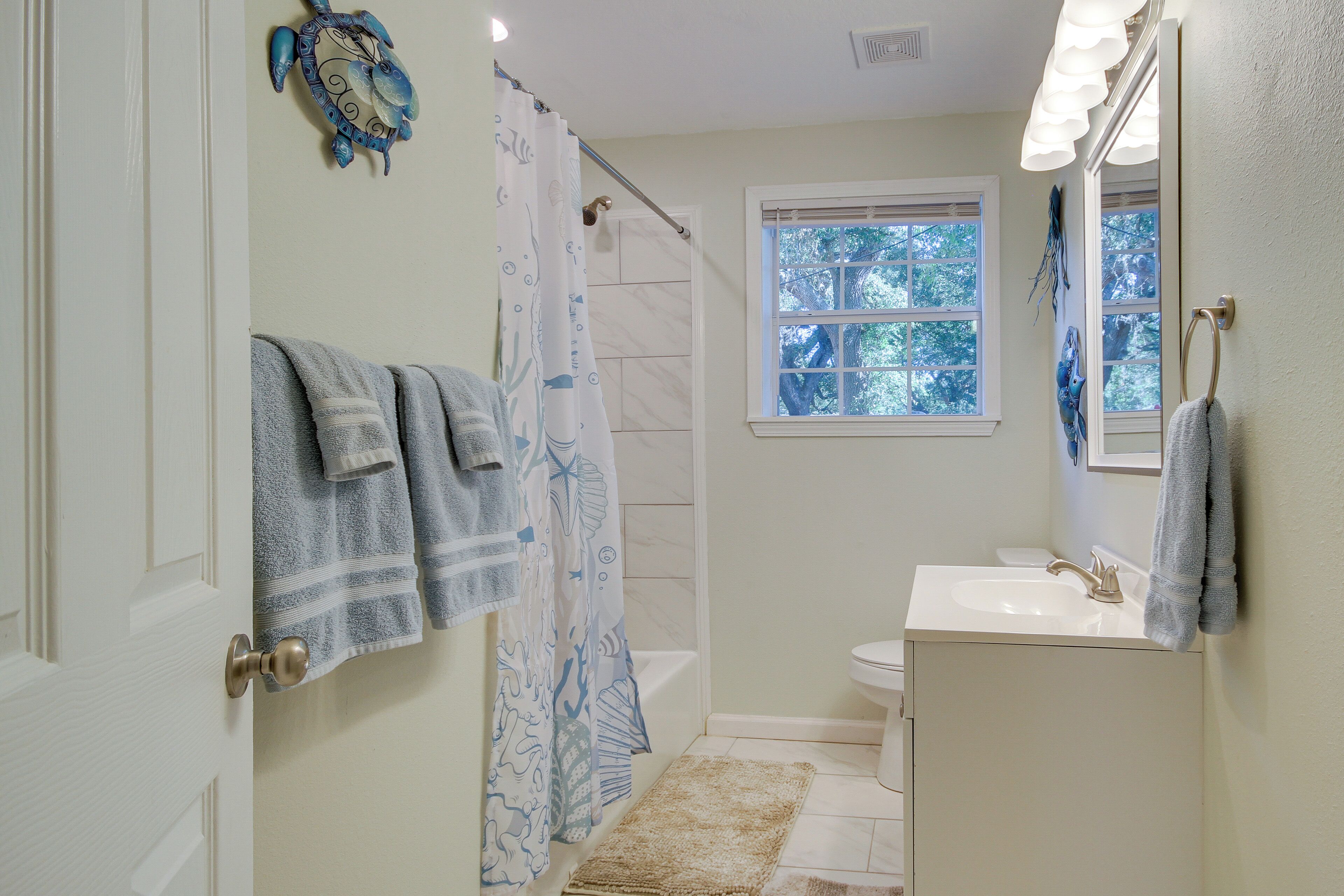 A bathroom with a shower, a sink, and a window.