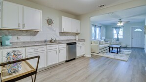 A spacious kitchen with white cabinets, a dishwasher, and a marble countertop. There is a dining area with a sofa and a coffee table. - Ample Trailer/rv Parking! Family Home in Gulfport (Gulfport)