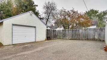 A garage with a closed white door, a gravel driveway, and a wooden fence.