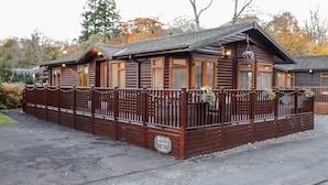 Una cabaña de madera con cerramiento exterior, varias ventanas y un letrero que indica que es un alojamiento rústico.
