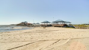 Une plage dotée de plusieurs structures abritées, d’une jetée qui s’avance dans l’eau et d’un rivage sablonneux.