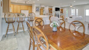Une salle à manger spacieuse avec une table et des chaises en bois, une cuisine avec des meubles en bois et un salon avec un canapé et une télévision.