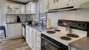 A kitchen with white cabinets, a stove, and a sink. - Prosperity Vacation Rental ~ 1 Mi to Lake Murray! (Prosperity)