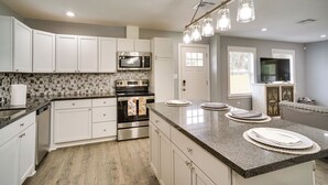 A modern kitchen with white cabinets, a stainless steel oven, a microwave, and a granite countertop. - Lake Charles Home w/ Gas Grill & Fenced-in Yard! (Lake Charles)