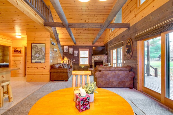 A wooden cabin interior with a dining area, seating, and a fireplace.