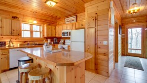 Cocina de cabaña de madera con una isla central, armarios de madera, un microondas y un refrigerador.