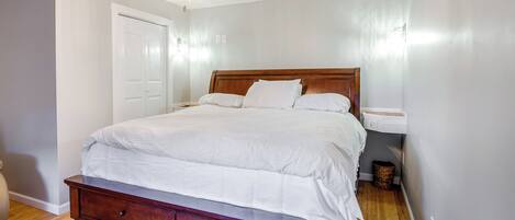 Un dormitorio con una cama de madera, un ventilador de techo y una mesita de noche.