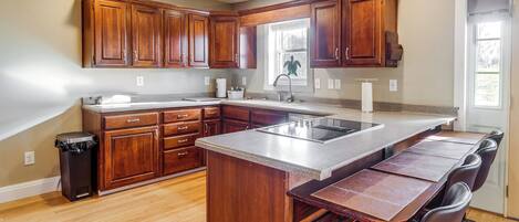 A kitchen with wooden cabinets, a granite countertop, and a built-in island with seating.