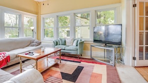 A living room with a sofa, a coffee table, a television, and a window with a view of trees. - Eau Claire Retreat: Close to Campus & Dtwn! (Eau Claire)