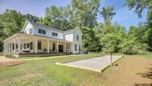 A two-story white house with a covered porch and a front yard.