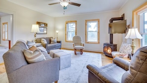 A living room with a fireplace, sofas, a chair, and a television. - Lovely Rural Hixton Farmhouse w/ Porch & Fire Pit! (Hixton)