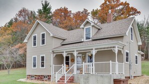 A two-story house with a porch, a chimney, and a stone foundation. - Lovely Rural Hixton Farmhouse w/ Porch & Fire Pit! (Hixton)
