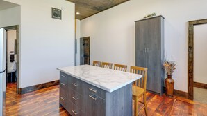 Eine Küche mit Marmorarbeitsplatte, Holzschränken und einem Essbereich mit Stühlen.