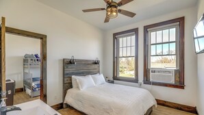 Ein Schlafzimmer mit Bett, Deckenventilator, Fenster mit Klimaanlage und Holz-Kopfstück.
