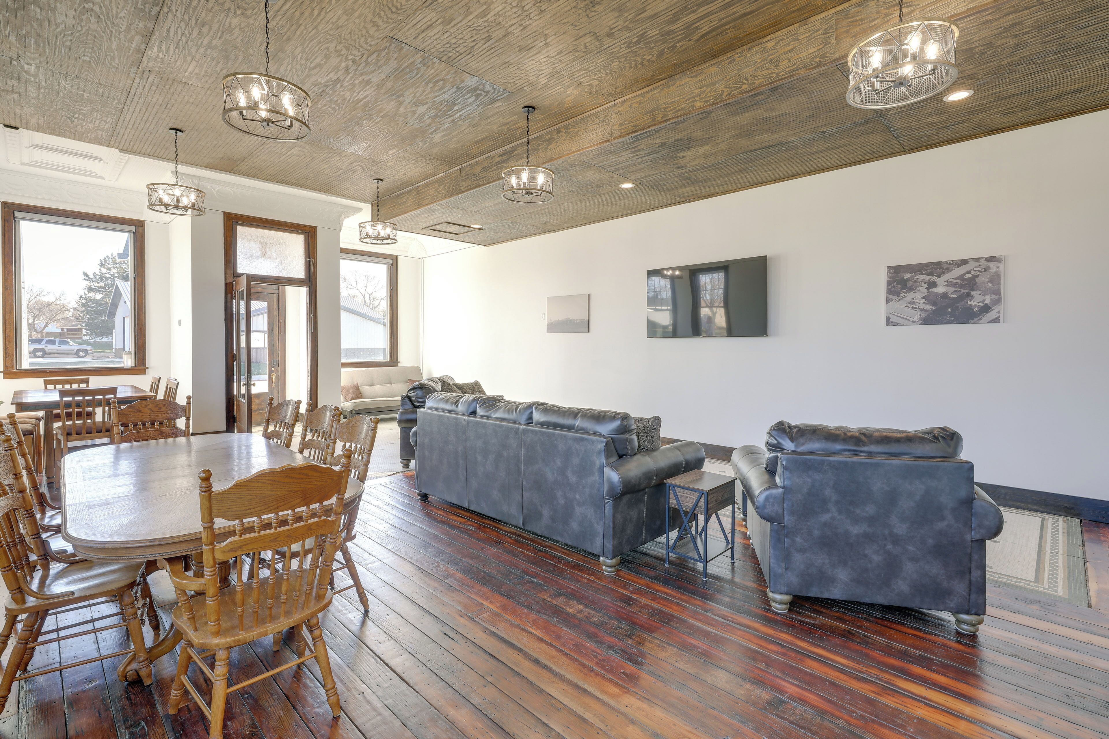 A spacious room with a wooden dining table surrounded by chairs, a gray sofa, and a blue armchair.