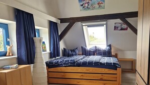 A bedroom with a loft bed, a window with curtains, a wooden wardrobe, and a wall with a picture.