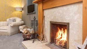 A cozy room with a fireplace, a sofa, and a television mounted on the wall. - Maxwelston Farmhouse (Girvan)