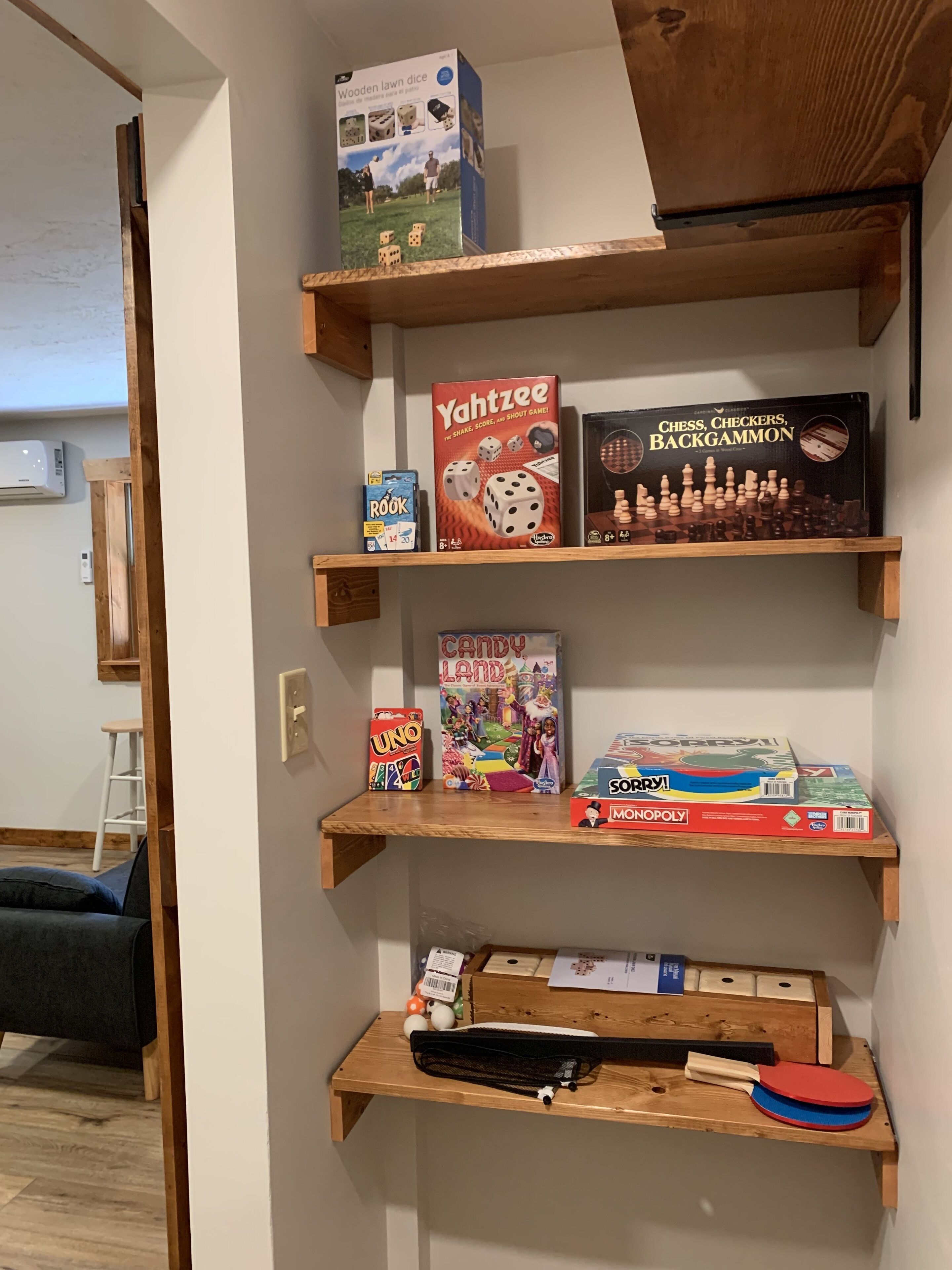 A shelf with various board games including Yahtzee, Chess Checkers Backgammon, Candy Land, UNO, and Monopoly.