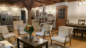 A cozy living room with a wooden coffee table, comfortable chairs, and a vase of flowers. - Red Stone Retreat-10 Min to Asheville, Game Room, Firepit, Quiet and Secluded  (Swannanoa)