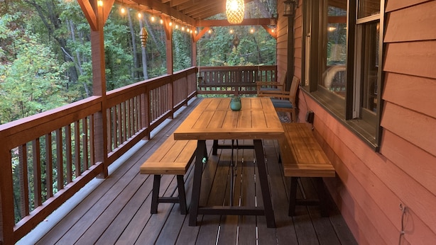 A wooden deck with a table and benches, overlooking a forested area. - Red Stone Retreat-10 Min to Asheville, Game Room, Firepit, Quiet and Secluded  (Swannanoa)