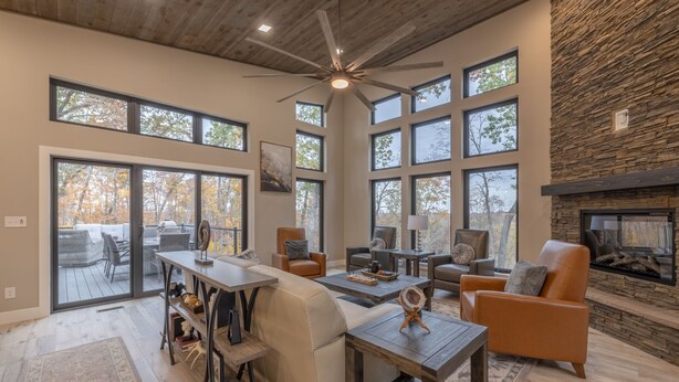 Un salón espacioso con chimenea, ventanas amplias y ventilador de techo.