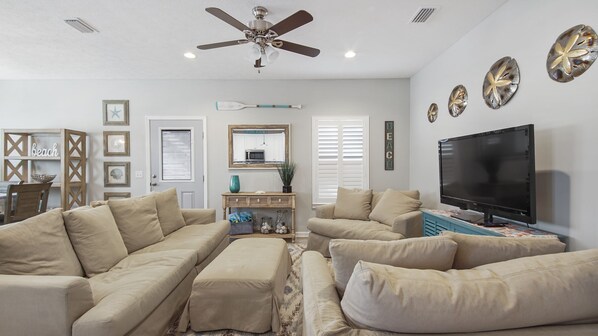 A living room with beige sofas, a TV, and decorative wall art.