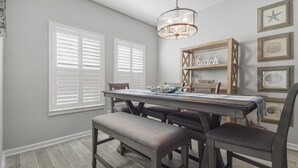 A dining area with a wooden table, chairs, and a chandelier. - 3 Bed 2 Bath house Chasing Sunsets Sleeps 7 (panama city beach)