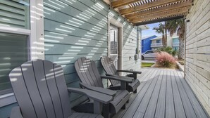 A covered porch with Adirondack chairs and a table, wooden deck, and a view of a residential street. - 3 Bed 2 Bath house Chasing Sunsets Sleeps 7 (panama city beach)