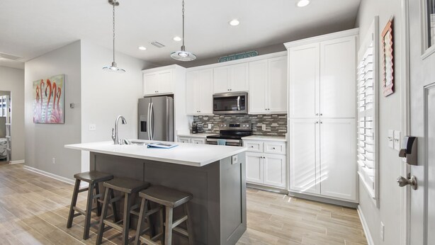 A modern kitchen with white cabinetry, stainless steel appliances, and a central island with bar stools. - 3 Bed 2 Bath house Chasing Sunsets Sleeps 7 (panama city beach)