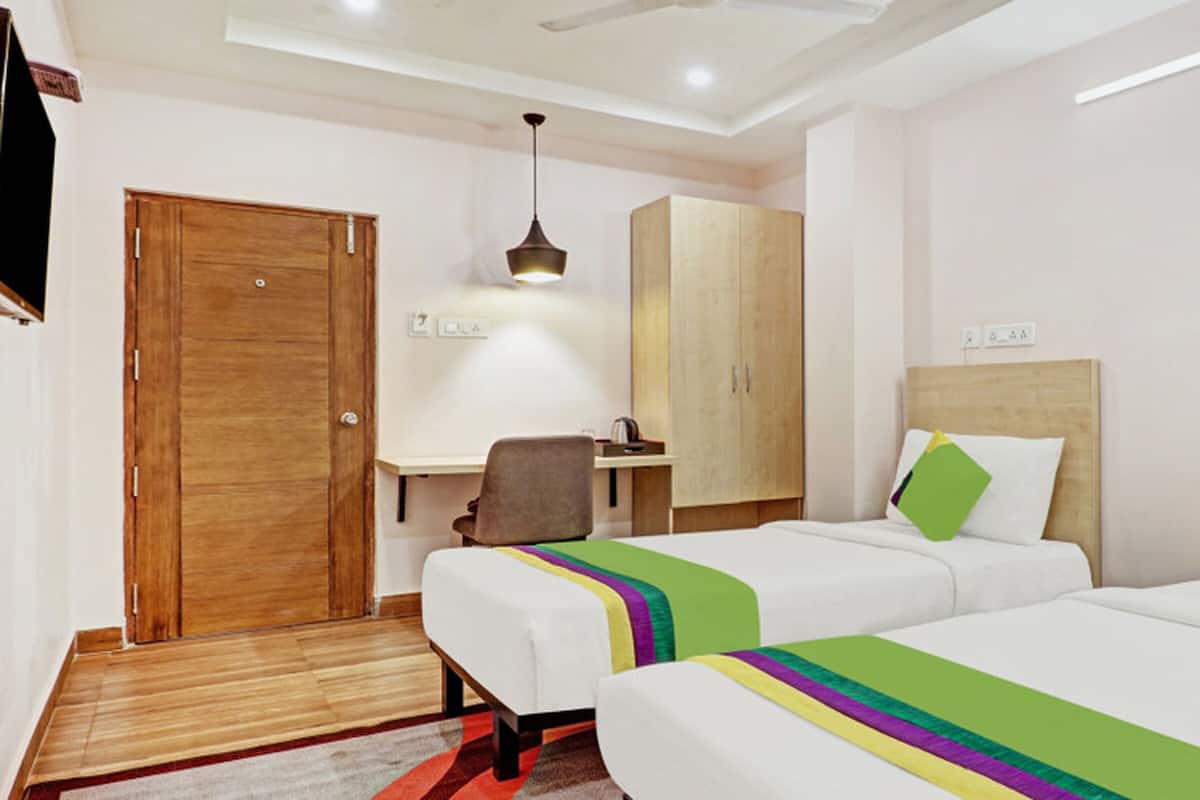Una habitación de hotel con dos camas, un escritorio, una silla y un armario.