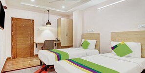 A hotel room with two beds, a desk, a chair, and a wardrobe. - DE CROWN LUXURY HOTEL (Kakinada)