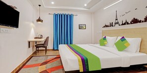 A hotel room with a bed, a desk, a chair, a blue curtain, and a wall with a cityscape mural. - DE CROWN LUXURY HOTEL (Kakinada)