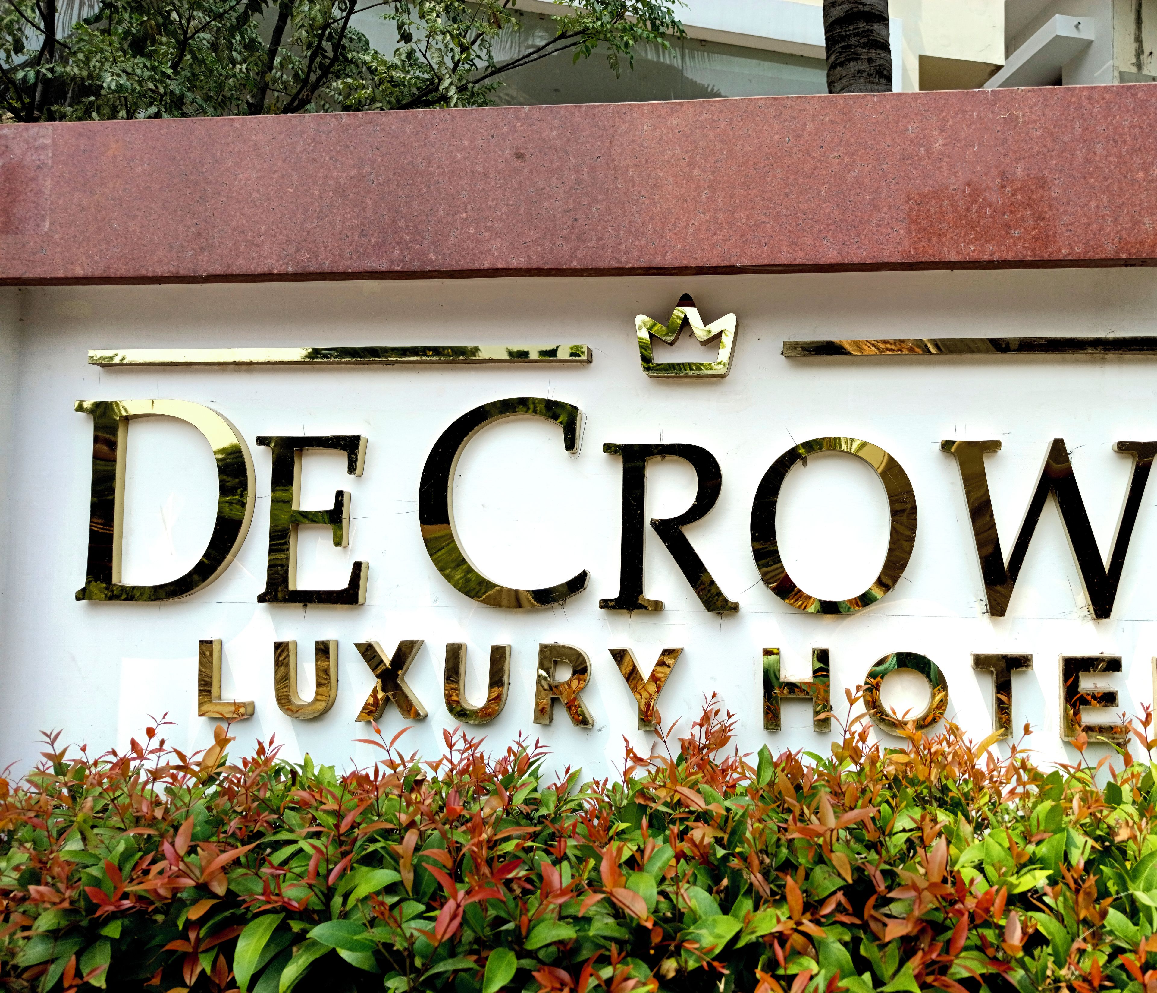 A sign for De Crown Luxury Hotel with a crown symbol above the name.