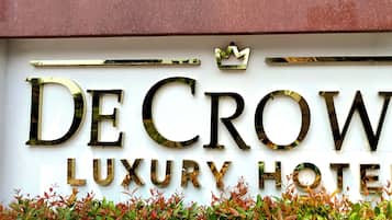A sign for De Crown Luxury Hotel with a crown symbol above the name.