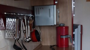 Et køkken med stålvask, kaffemaskine og ophængte køkkenredskaber.
