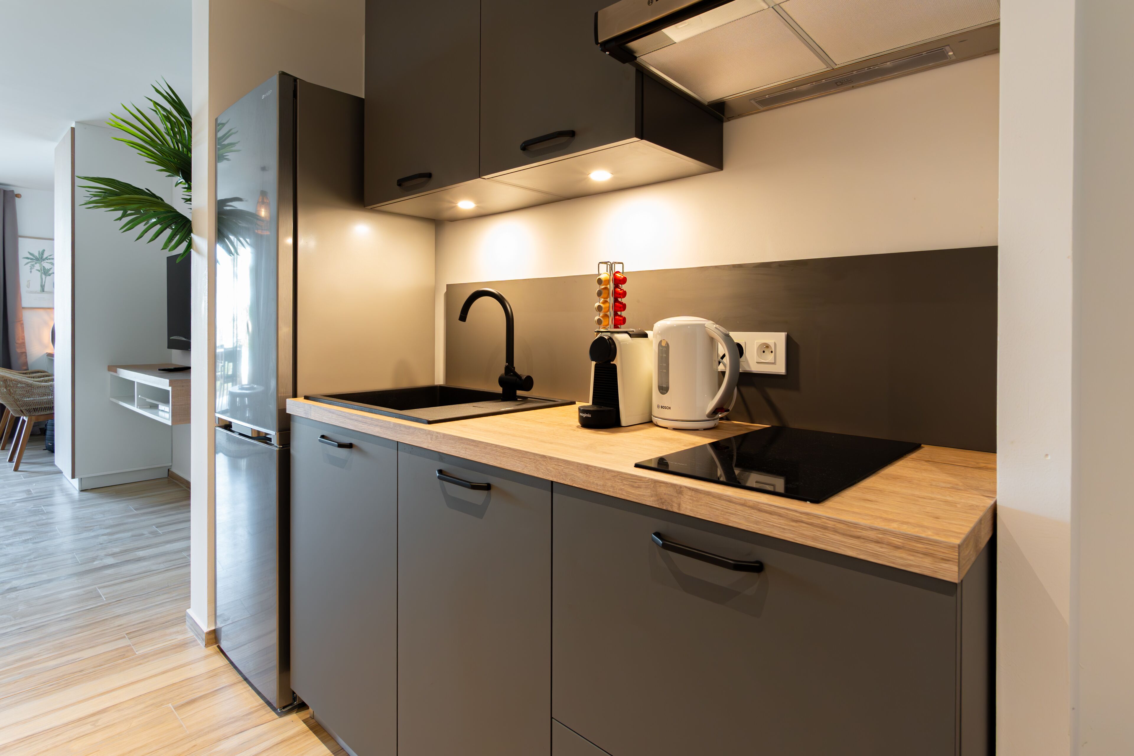 A modern kitchen with a wooden countertop, a black faucet, and a coffee maker.