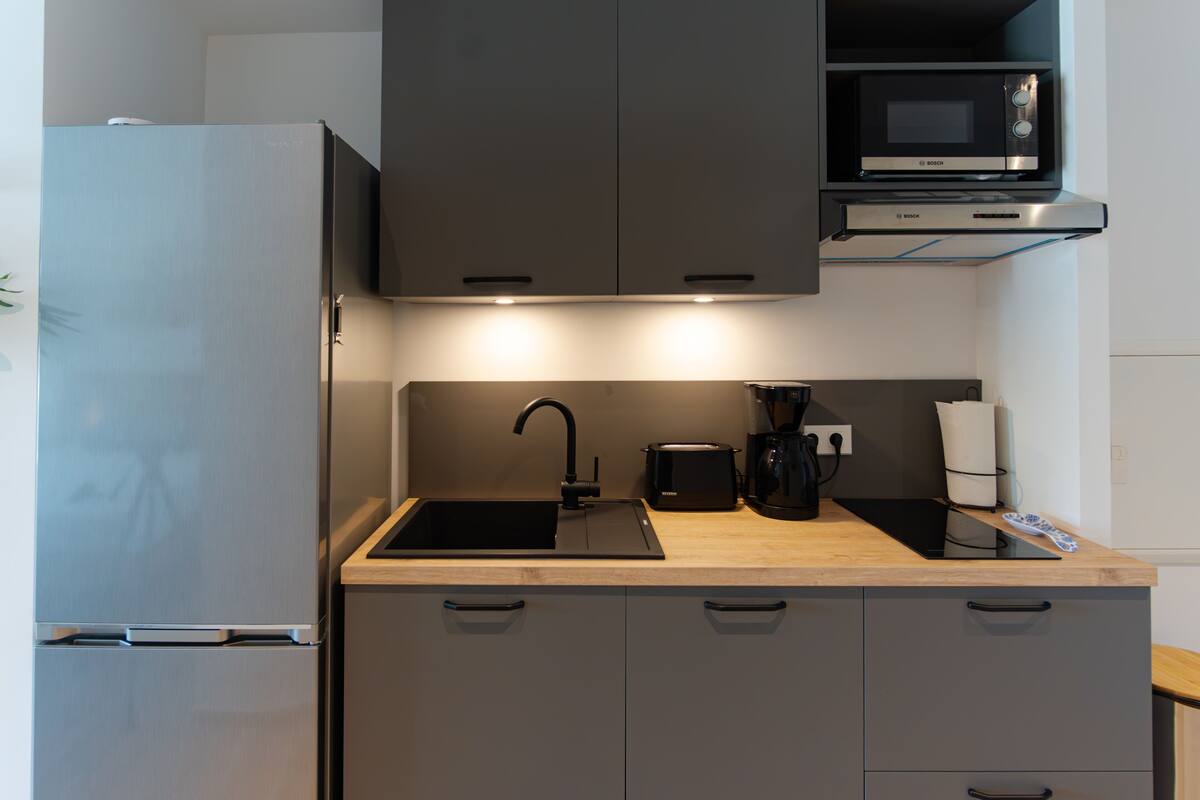 A compact kitchen with a refrigerator, microwave, sink, and cabinets.
