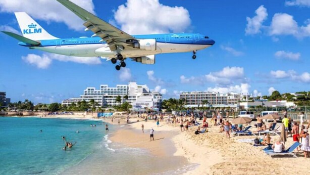 Een strand met een KLM vliegtuig dat landt.