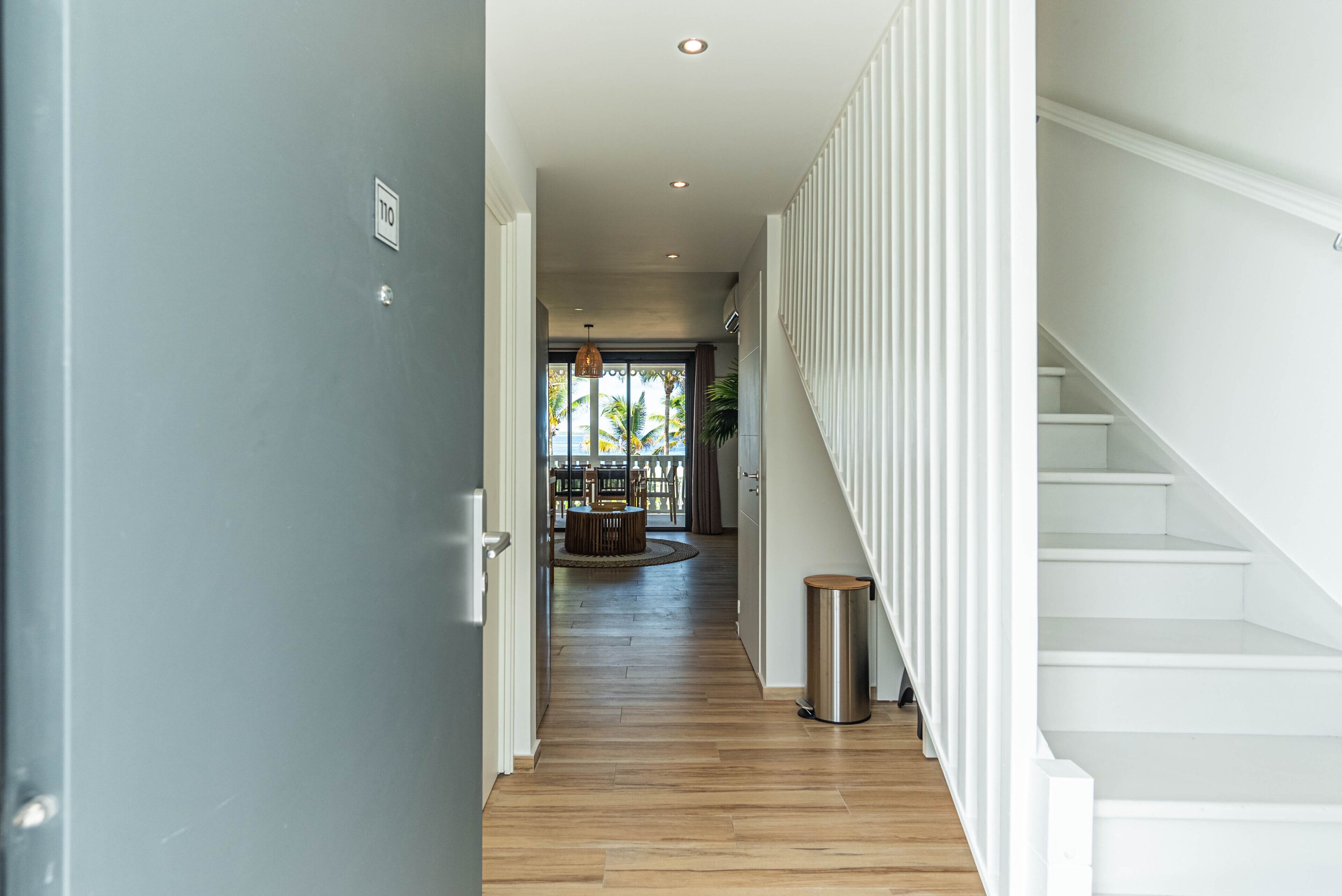 A hallway with a wooden floor leading to a staircase.