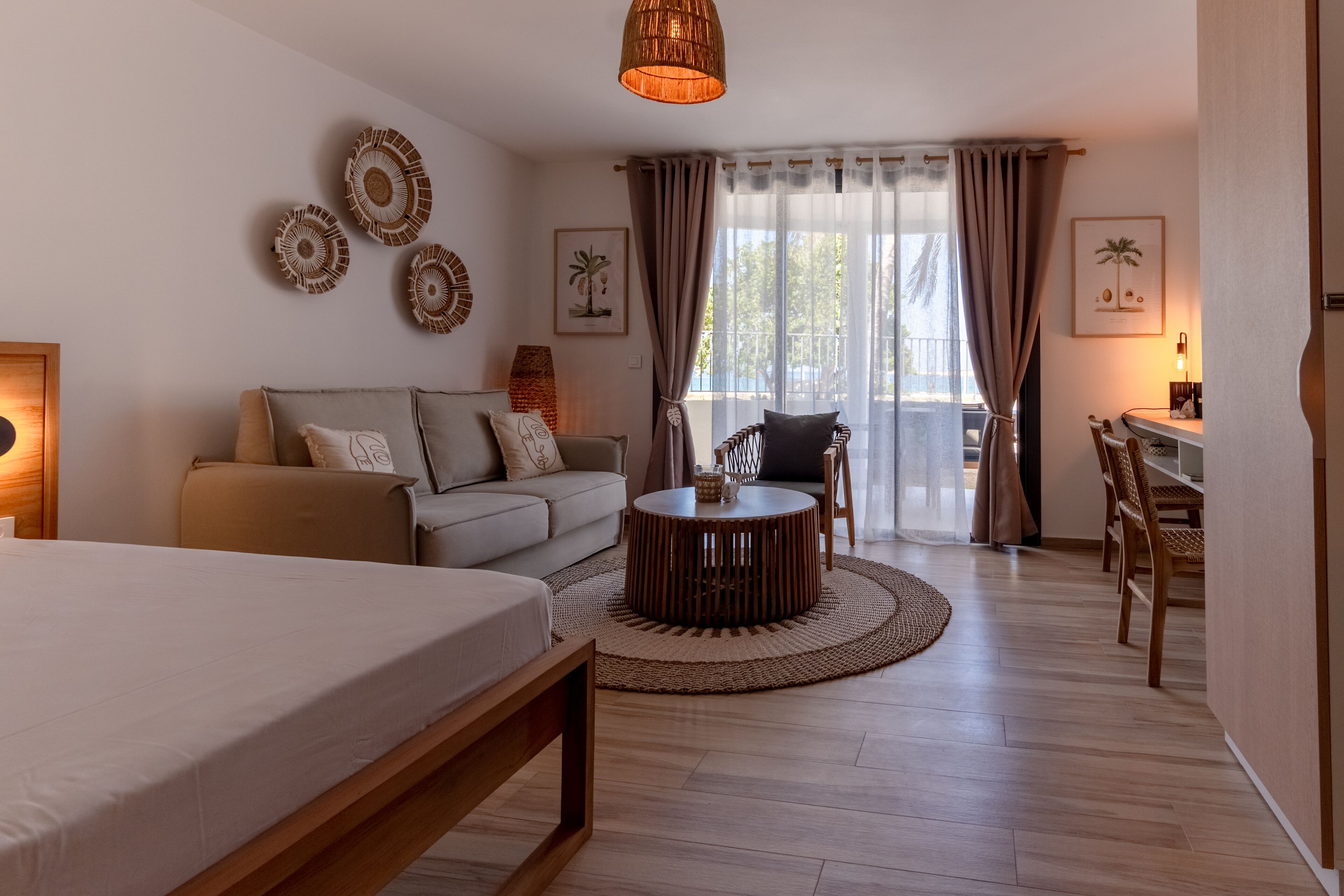 Una habitación de hotel moderna con una cama, un sofá, una mesa redonda de madera y un comedor con sillas.
