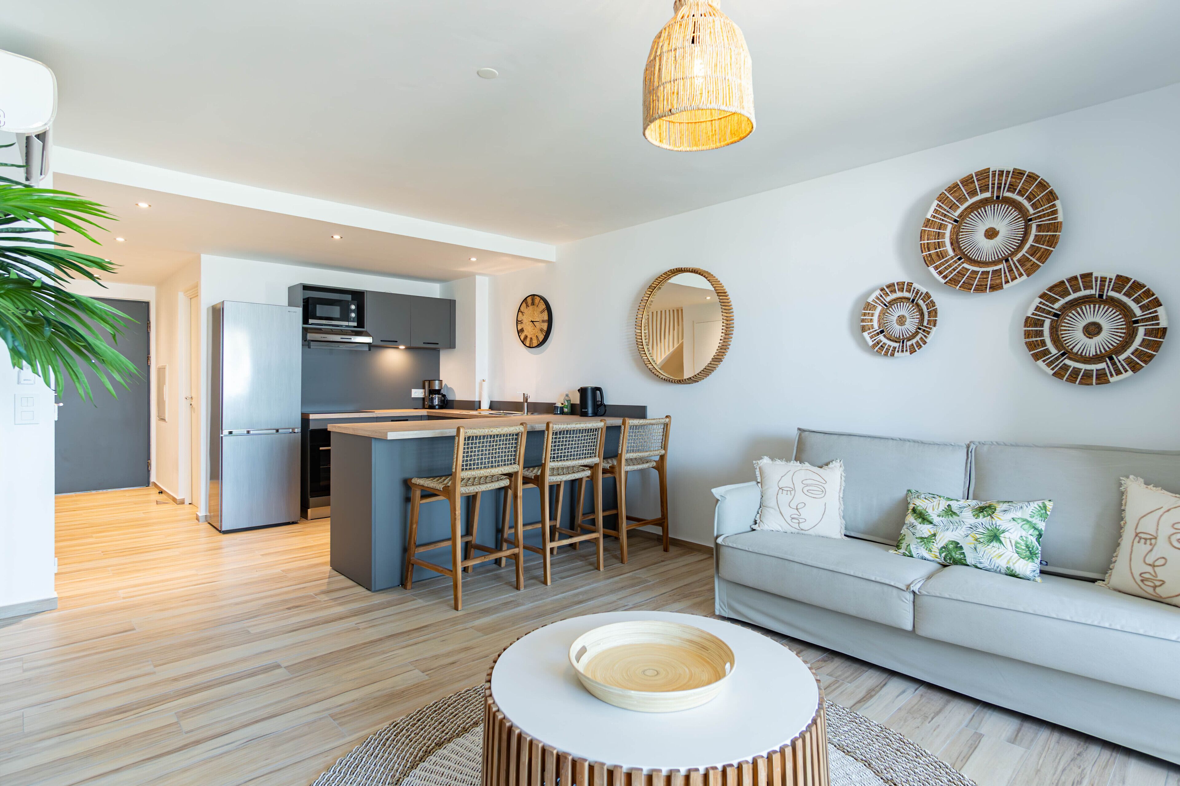A modern living room with a sofa, a coffee table, and a kitchen area with a dining set.