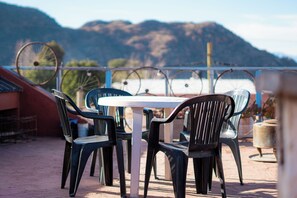 A patio with a table and chairs, overlooking a body of water and mountains. - HOSTEL La Casa de Li  En (Chilecito)