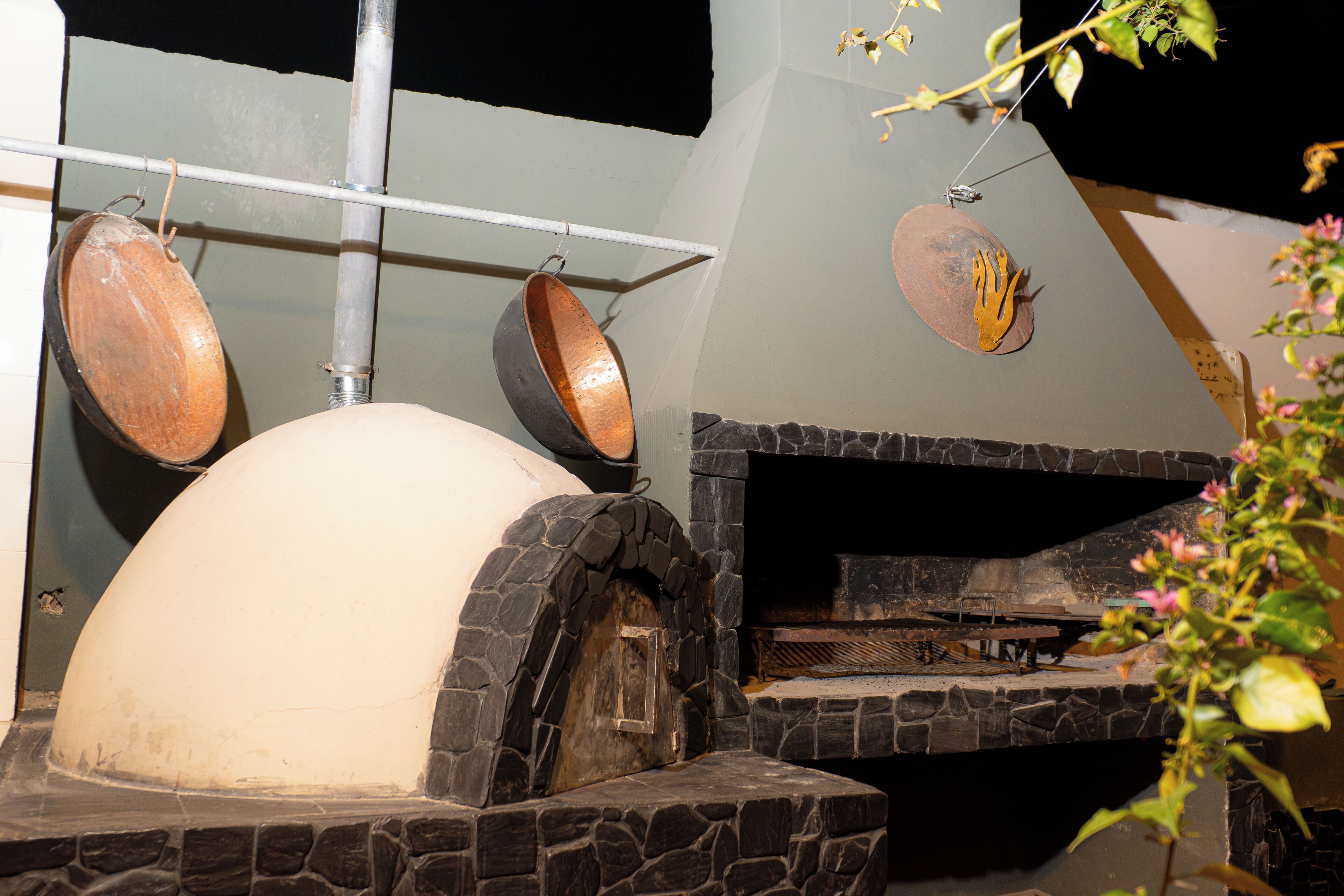 A stone oven with a chimney, a metal rack with pots, and a white dome structure.