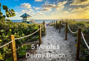 A sandy beach path leading to a lifeguard tower with the text "5 Minutes Delray Beach". - Spacious Designer Home Htd Pool Near Atlantic Ave (Delray Beach)