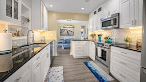 A modern kitchen with white cabinetry, a central island, a microwave, and an oven. - Waterfront Htd Pool, Spa, Billiards, Lanai, Canal (Delray Beach)