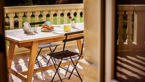 An outdoor patio with a wooden table set for breakfast, including croissants, a coffee cup, and a teapot. - Château de la Grange Moreau (Vallon-sur-Gée)