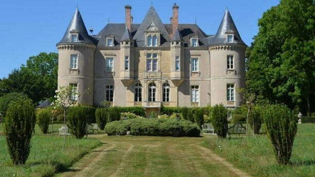 A large, historic building with multiple towers and a symmetrical facade, surrounded by well-maintained gardens and a clear sky. - Château de la Grange Moreau (Vallon-sur-Gée)