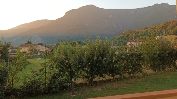 Une vue d’un paysage montagneux, avec des maisons au premier plan et un ciel dégagé.